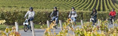 Photo de personnes en mobylettes au milieu des vignes